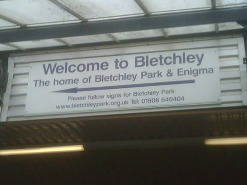 Sign at a train station saying "Welcome to Bletchley. The home of Bletchley Park & Enigma."