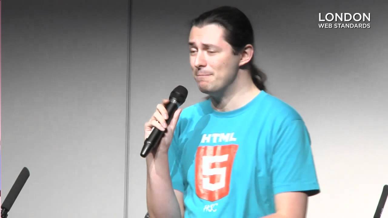 Photo of me holding a microphone. I'm wearing a T-Shirt with the HTML5 logo on it.
