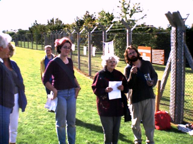 Several protesters hold signs outside the base.