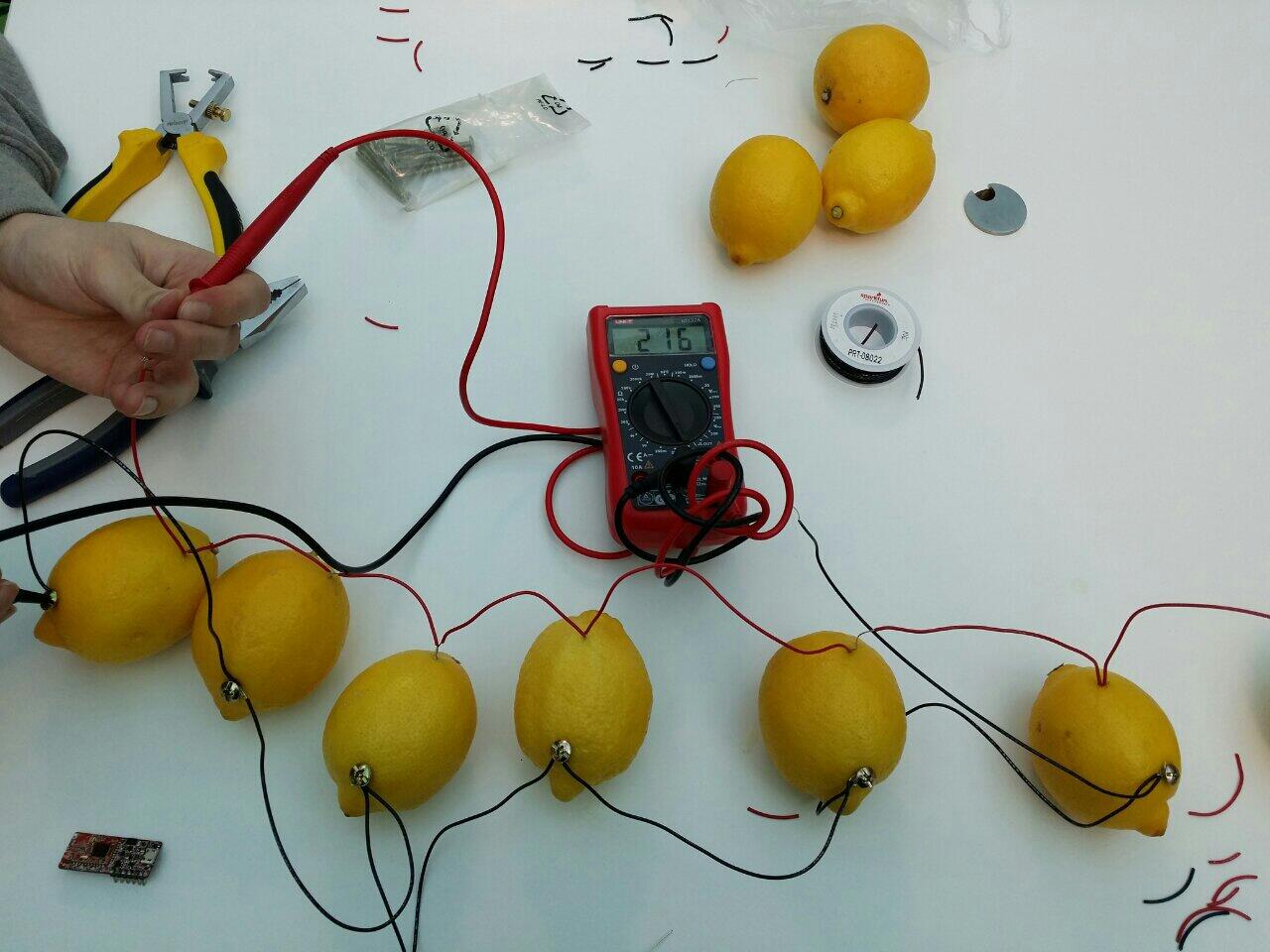 Photo of six lemons on a table. They're wired up to a multimeter and producing a trickle of current.