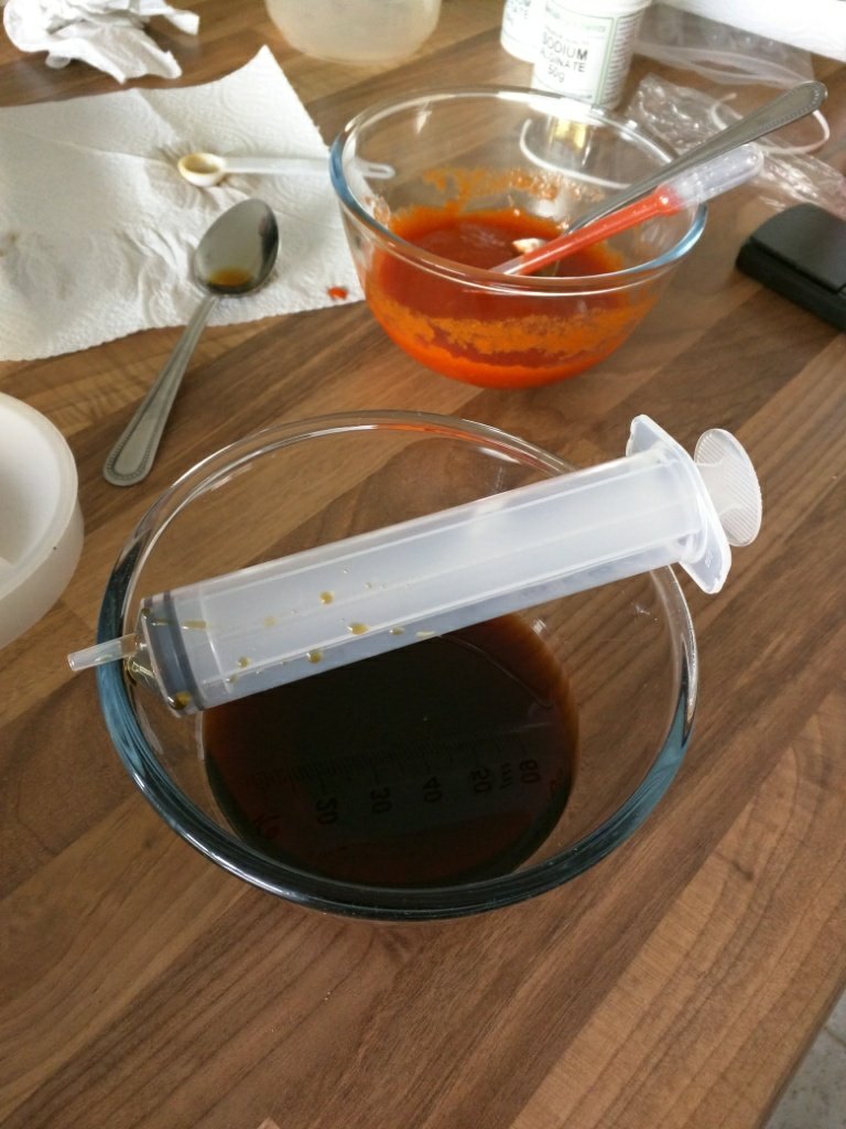 A food syringe over a bowl of soy sauce