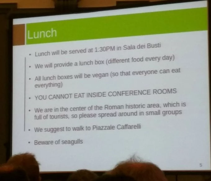 A projected screen at a conference, it says that all lunch boxes will be vegan.