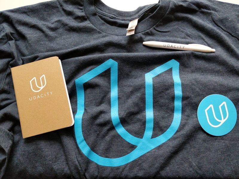 Photo of a Udacity T-Shirt, notebook, pen, and sticker