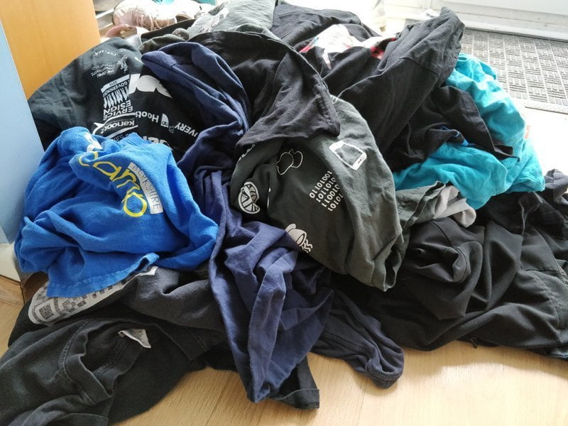 A huge pile of old t-shirts, each covered in conference logos.