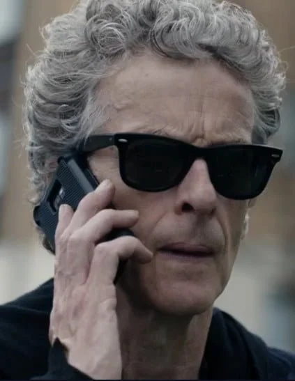 The doctor wearing sunglasses and holding a phone.