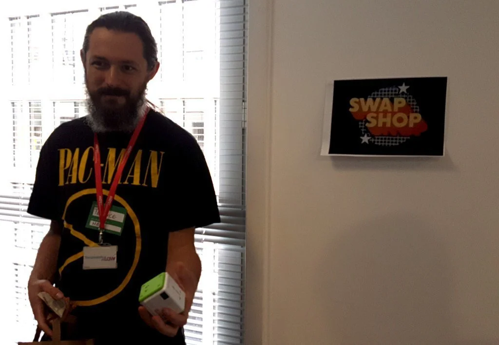 A bearded geek holding a mysterious cube. A sign in the background says "Swap Shop".