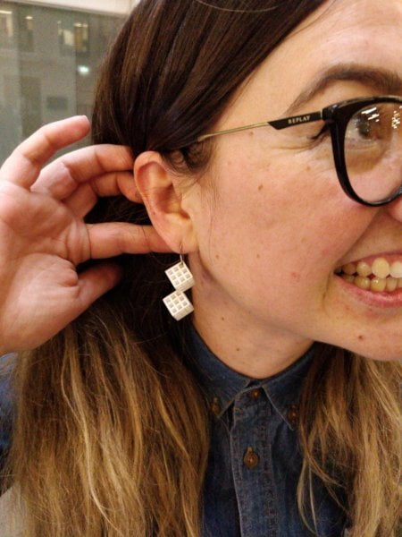 A woman with 3D printed cubes as earrings.
