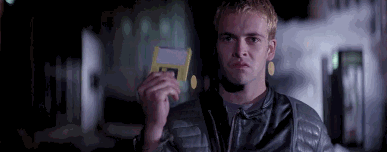 Jonny Lee Miller in the film Hackers. He is holding a floppy disk.