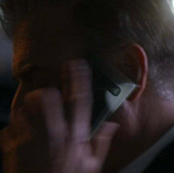 A dark shot of Jack holding a phone.