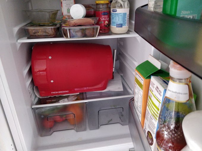 A big red cask taking up a shelf in the fridge.