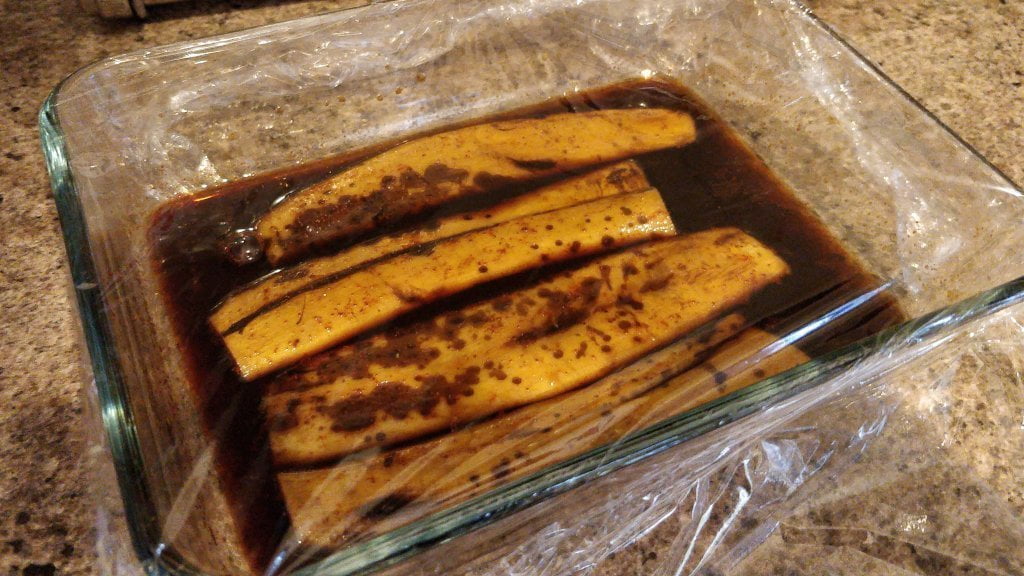 Strips of banana peel marinating in a thick black liquid.