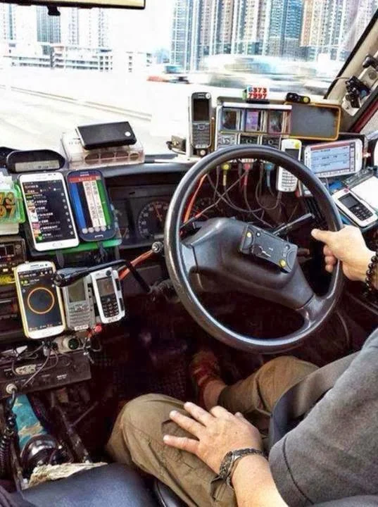 Photo of the inside of a Hong Kong taxi. There are about a dozen different phones attached to the dashboard - each running a different app.