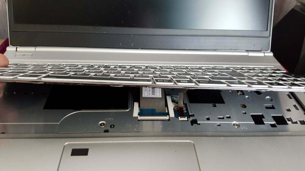 A keyboard being lifted out of a laptop.