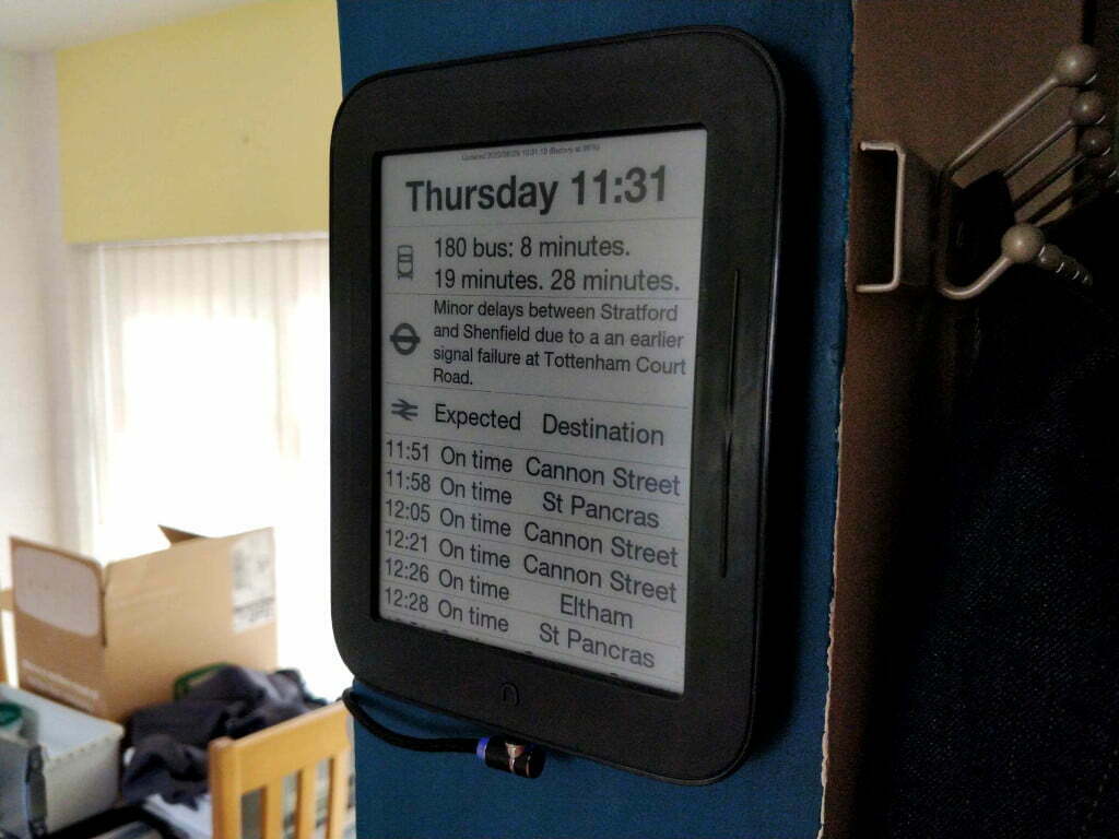 An eInk screen which is displaying the times until the next bus, what delays there are on the tube, and then a bunch of train departure times.