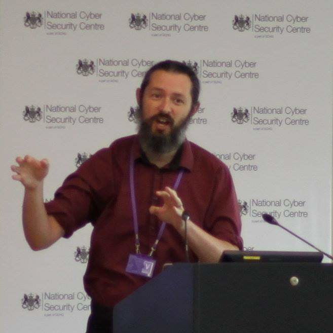 Photo of Terence presenting. The background has the NCSC logo.