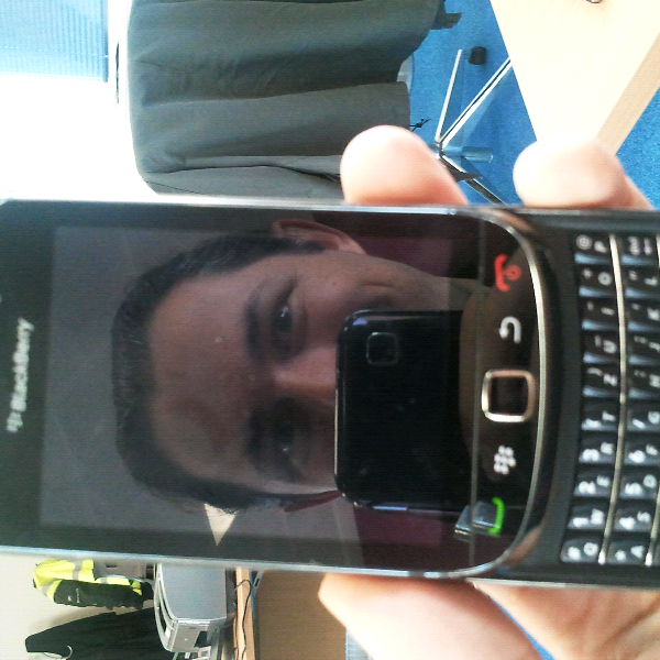Photo of me taking a photo of my BlackBerry. My face is reflected in the screen.