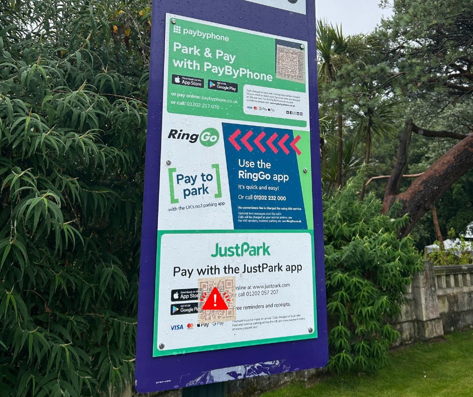 A car park payment information screen. There are two fake QR codes stuck to it.