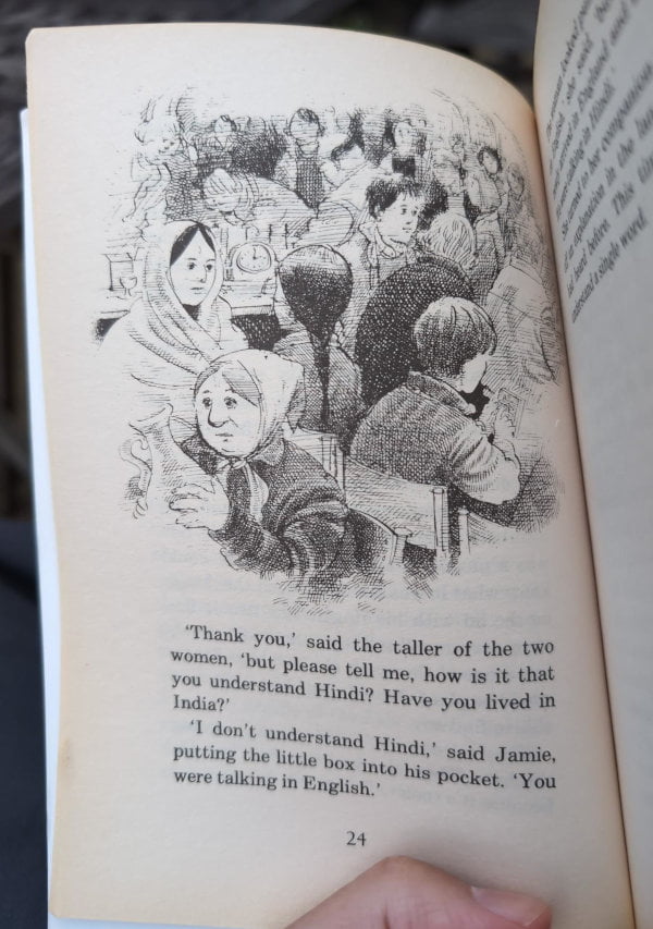 Monochrome illustration of people in a jumble sale. The text reads "'Thank you,' said the taller of the two women, 'but please tell me, how is it that you understand Hindi? Have you lived in India?' - 'I don't understand Hindi,' said Jamie, putting the little box into his pocket. 'You were talking in English.'