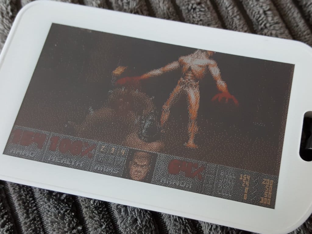 A very pixelated screenshot from the Original Doom displayed on an eInk badge.