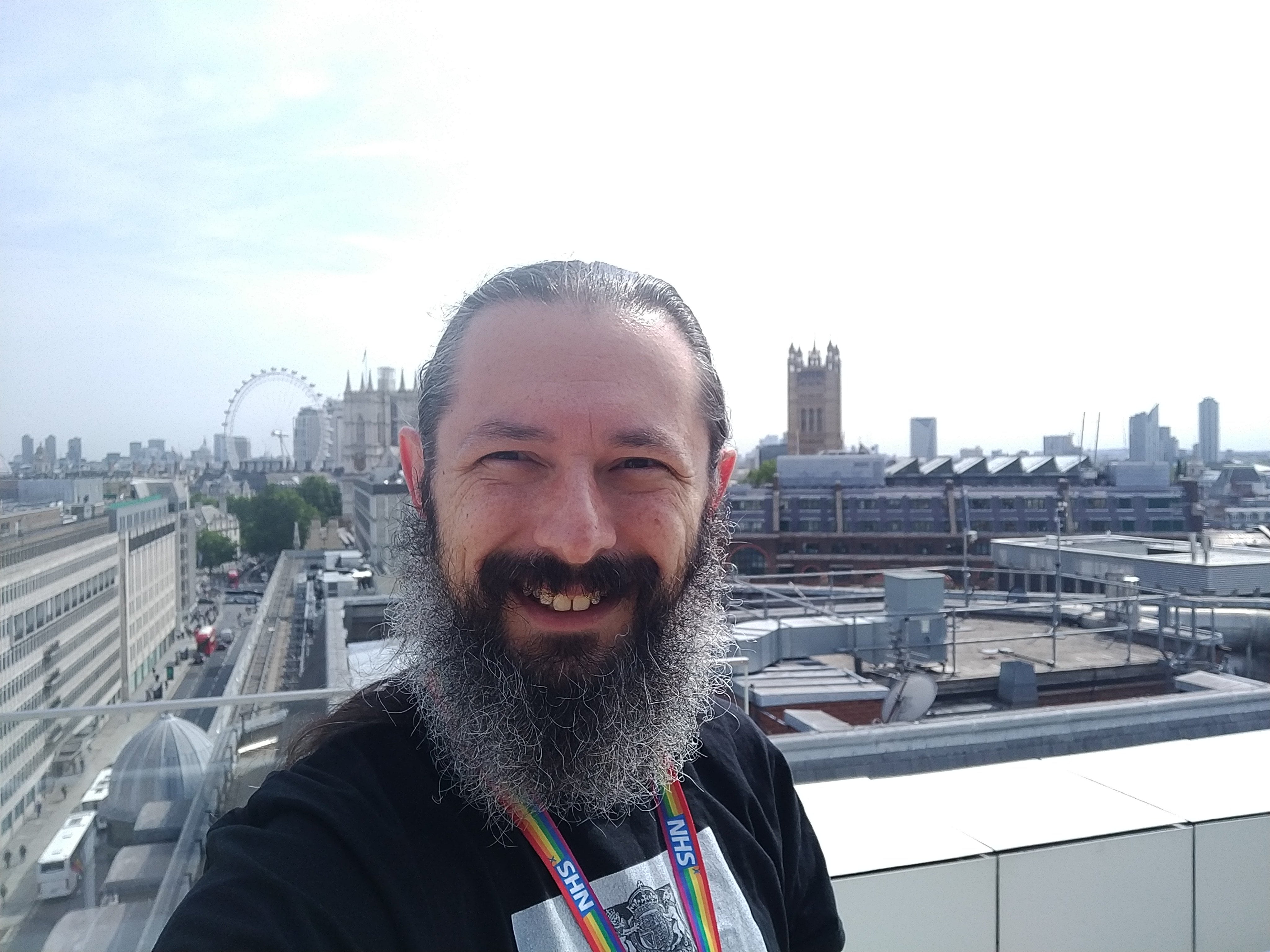 Selfie of me standing on a London roof. The palace of Westminster is in the background.