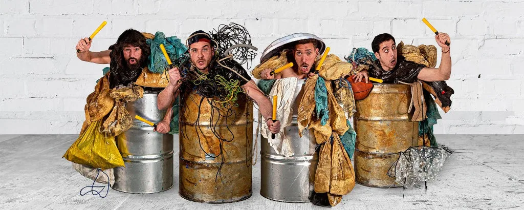 Four men in trash-cans, playing them like instruments.